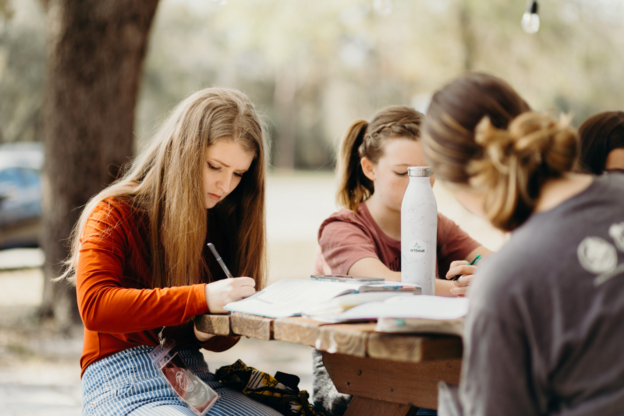 women writing in books on a picnic table